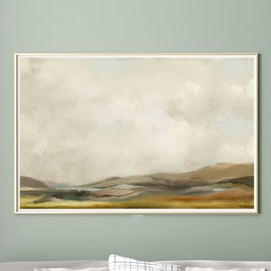 May include: A light green wall with a framed landscape painting of a cloudy sky over rolling hills. A white sofa with black and white patterned cushions sits in front of the painting. A white coffee table with a book and a vase of dried grasses sits in front of the sofa.