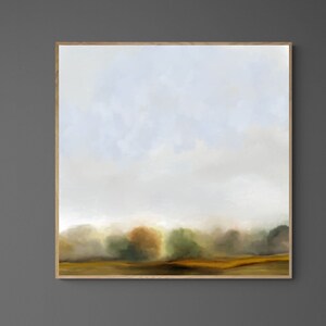 Op de afbeelding: Een ingelijst abstract landschapschilderij met een gedempte kleurenpalet van blauw, groen en bruin. Het schilderij toont een mistig veld met bomen in de verte. Het schilderij hangt aan een grijze muur boven een witte open haard met een zwarte vuurhaard.