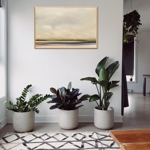 May include: A minimalist living room with a framed abstract landscape painting on the wall, three potted plants, a patterned rug, and a wooden coffee table.