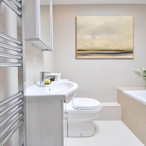 May include: A white bathroom with a white toilet, a white sink, a chrome towel rack, a bathtub, and a framed abstract landscape painting on the wall.