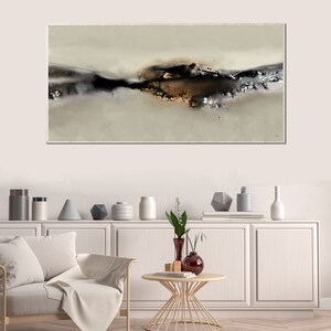 May include: Abstract painting with a brown, black, and white color scheme. The painting is on a canvas and is framed. The painting is hanging on a white wall in a living room setting.