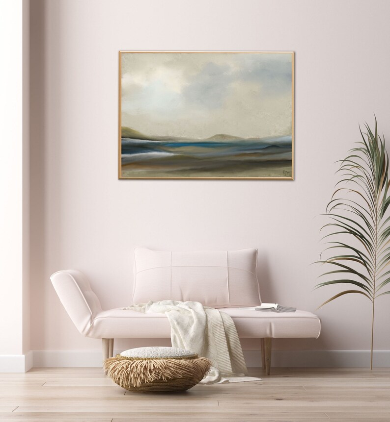 K&ouml;nnte beinhalten: Ein gerahmtes abstraktes Landschaftsbild in gedeckten T&ouml;nen von Blau, Gr&uuml;n und Braun. Das Bild zeigt eine ferne K&uuml;ste mit einem Gew&auml;sser im Vordergrund. Das Bild h&auml;ngt an einer wei&szlig;en Wand in einem Wohnzimmer.
