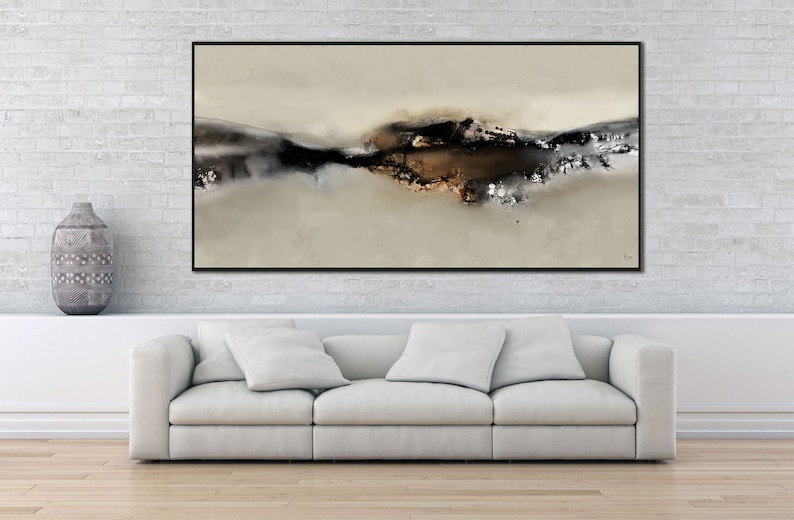 May include: Abstract art print with a black frame, featuring a brown and gray landscape with a white background. The print is hanging on a white brick wall above a white couch.
