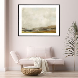 May include: A framed landscape painting with a muted colour palette. The painting depicts a rolling hillside with a cloudy sky above. The painting is framed in black and is hanging on a white wall.