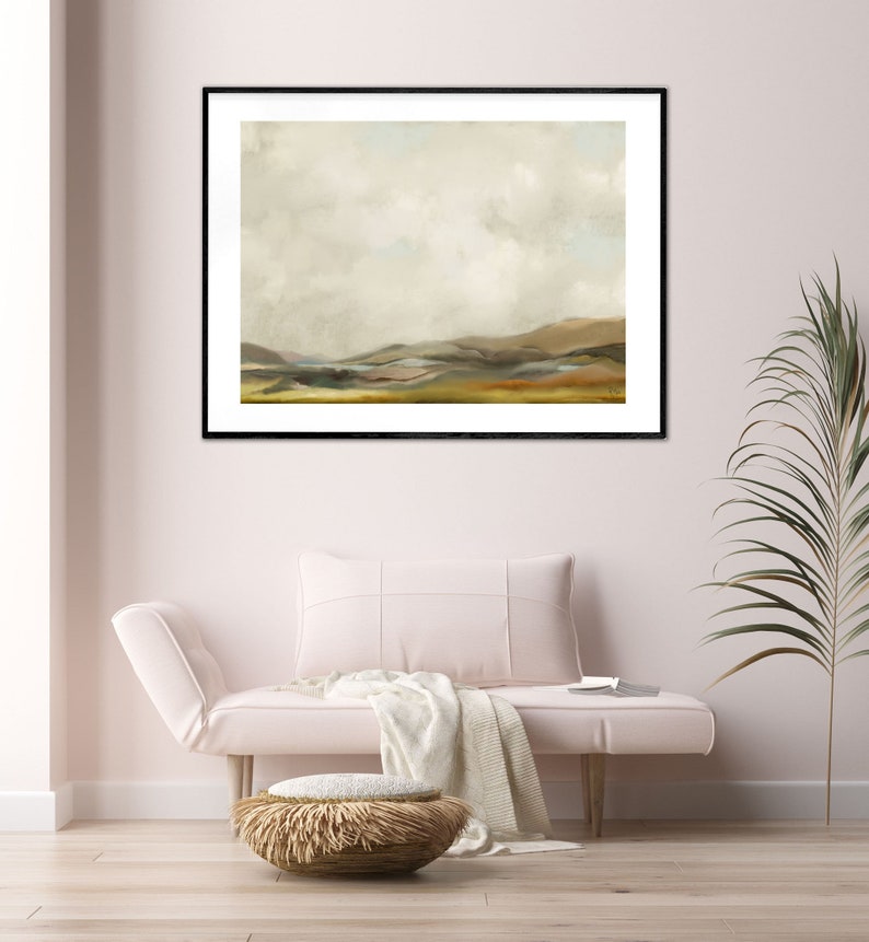 May include: A framed landscape painting with a muted colour palette. The painting depicts a rolling hillside with a cloudy sky above. The painting is framed in black and is hanging on a white wall.