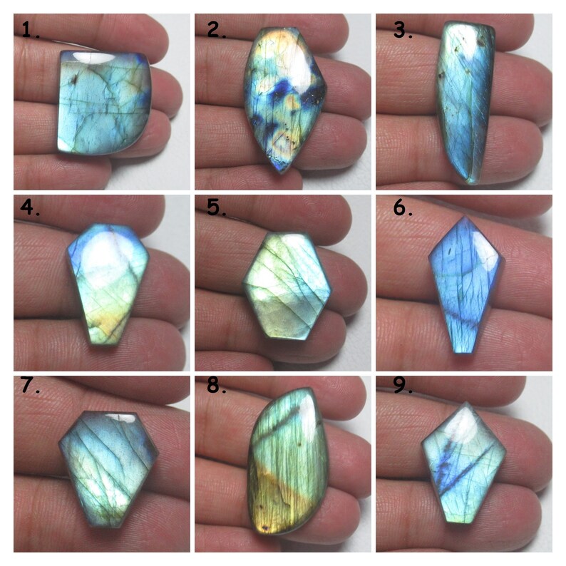 May include: Nine iridescent labradorite gemstones of various shapes and sizes, including oval, teardrop, and kite shapes. The stones have a blue-green base with flashes of gold and silver.