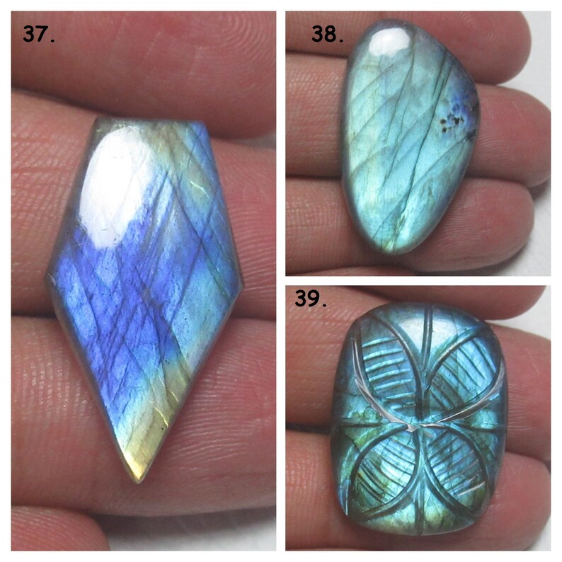 May include: Three labradorite gemstone cabochons, one with a diamond shape, one oval, and one rectangular with a carved design. The stones are blue, green, and gold.