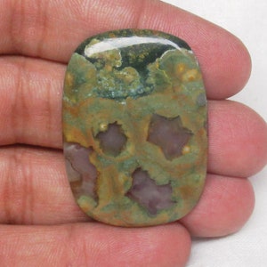 May include: A green, brown, and purple oval-shaped polished stone with a unique pattern. The stone has a smooth, glossy finish.