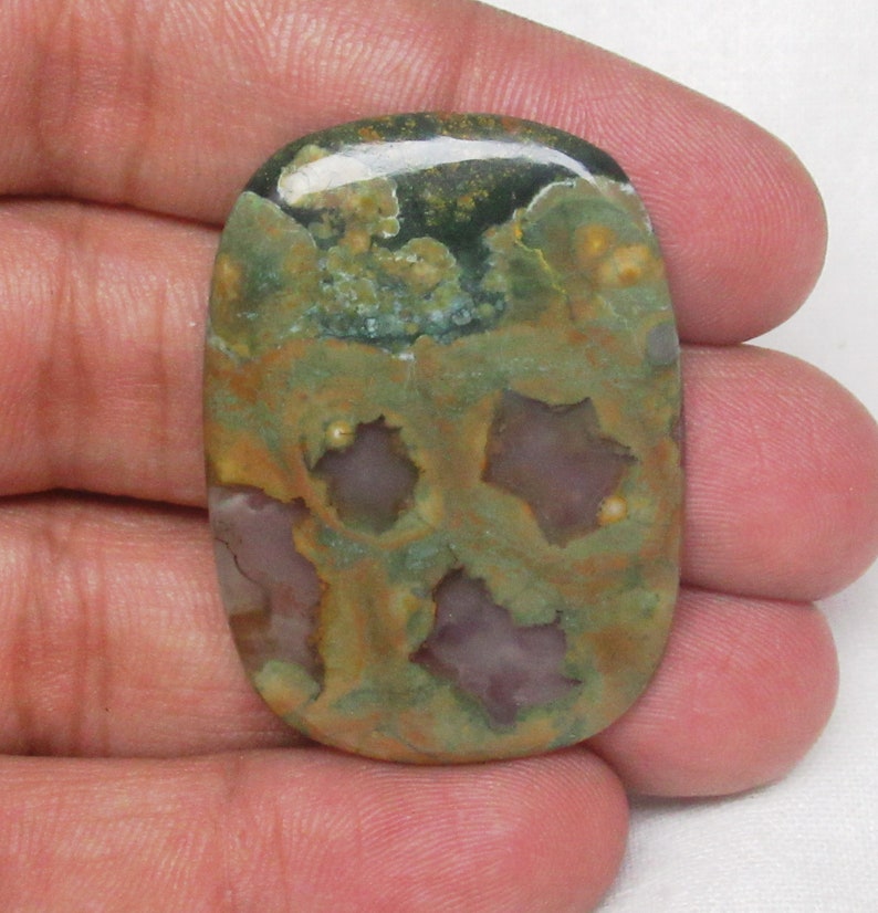 May include: A green, brown, and purple oval-shaped polished stone with a unique pattern. The stone has a smooth, glossy finish.