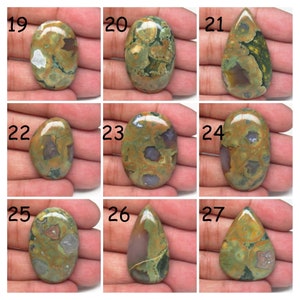May include: Nine cabochon gemstones with a green, brown, and white pattern. The stones are oval and teardrop shaped. The stones are numbered 19 through 27.