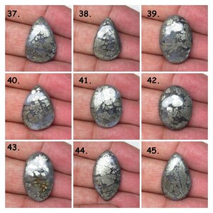 May include: Nine silver and gray pear-shaped and oval cabochon gemstones with a pyrite pattern.