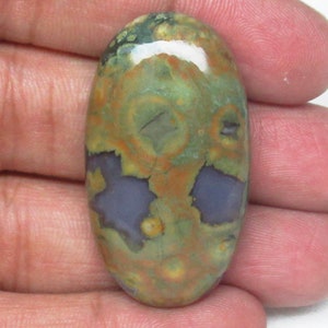 May include: A green, brown, and purple oval-shaped cabochon gemstone with a unique pattern of swirls and spots.