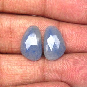 May include: Two light blue faceted gemstone drops. The stones are pear shaped and have a translucent appearance.