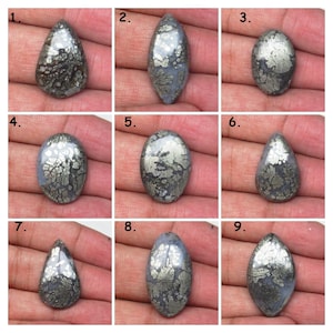 May include: Nine cabochon gemstone cabochons with a silver and gray color. The cabochons have a unique pattern of silver pyrite inclusions.