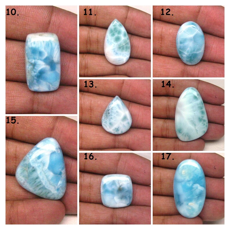 May include: A collection of seven blue and white gemstone cabochons in various shapes, including oval, pear, rectangle, and triangle. The cabochons are displayed on a hand.