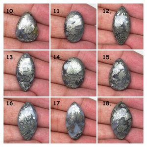 May include: Nine cabochon cut, pear-shaped, silver and black, dendritic agate gemstones. The stones are arranged in three rows of three.