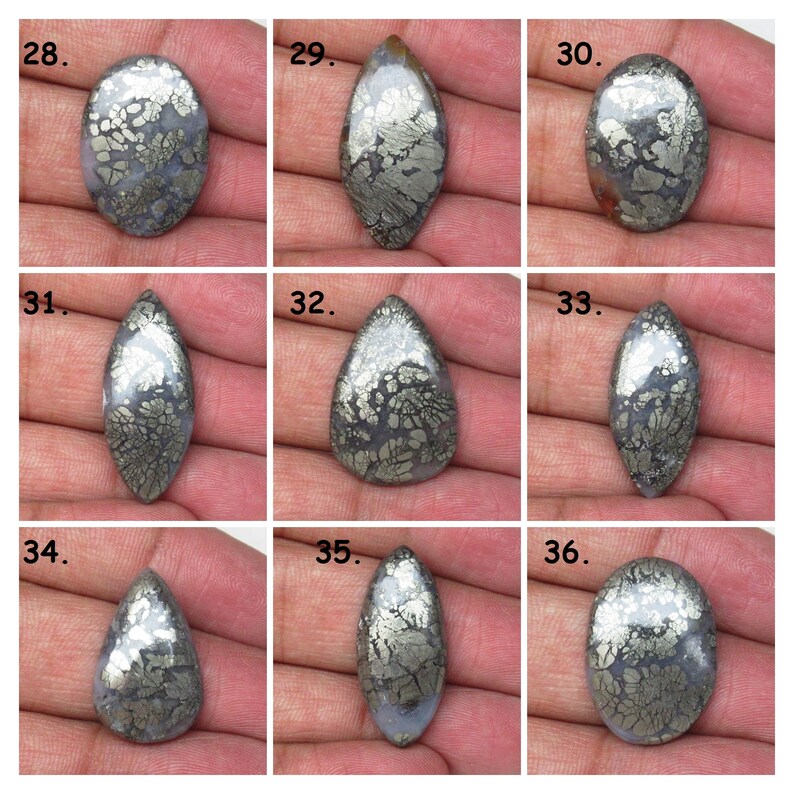 May include: Nine cabochon gemstone cabochons with a silver and gray marbled pattern. The cabochons are arranged in three rows of three. The cabochons are all different shapes and sizes.
