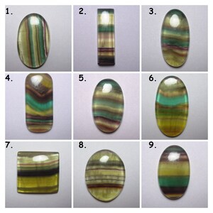 Puede incluir: Nueve piedras preciosas de fluorita talladas en cabuj&oacute;n de diferentes formas y tama&ntilde;os. Las piedras son todas verdes, amarillas y moradas con un patr&oacute;n de bandas.