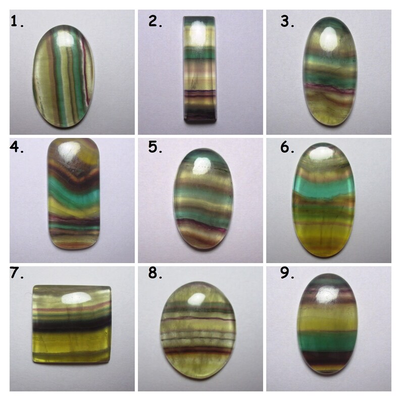 Puede incluir: Nueve piedras preciosas de fluorita talladas en cabuj&oacute;n de diferentes formas y tama&ntilde;os. Las piedras son todas verdes, amarillas y moradas con un patr&oacute;n de bandas.