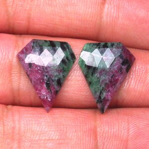 May include: Two green and pink gemstone cabochons in a diamond shape.