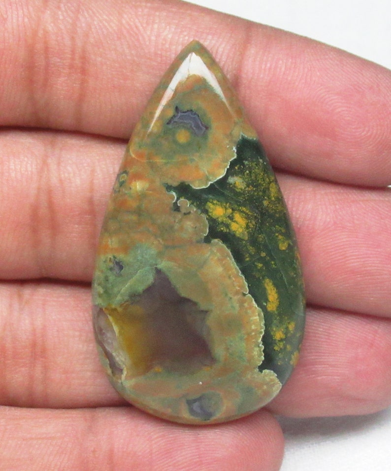 May include: A teardrop-shaped green, brown, and yellow gemstone cabochon with a mottled pattern.