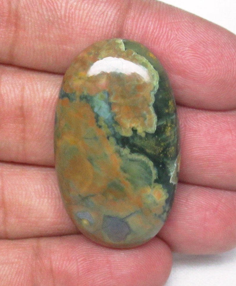 May include: A green, brown, and orange oval-shaped gemstone with a mottled pattern.