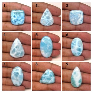 May include: Nine different shapes and sizes of blue and white gemstone cabochons. The cabochons are set in a hand for size comparison.