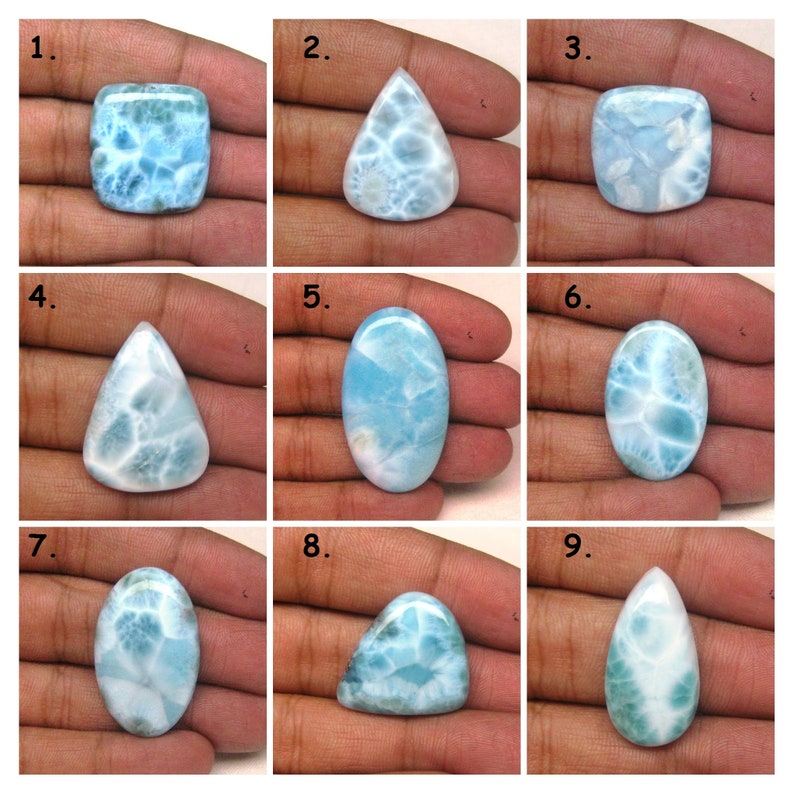 May include: Nine different shapes and sizes of blue and white gemstone cabochons. The cabochons are set in a hand for size comparison.