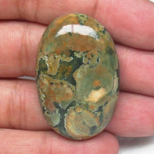 May include: A green, brown, and white oval-shaped cabochon gemstone with a mottled pattern.