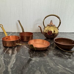 Peut inclure: Ensemble de trois mugs en céramique avec une finition mate et mouchetée. Les tasses sont de couleur crème, marron clair et marron foncé. Chaque mug a un design simple et minimaliste.