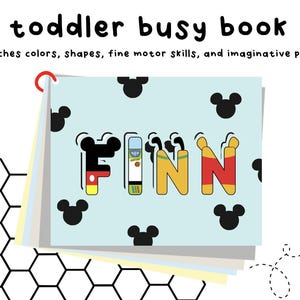 May include: A blue and white busy book with the name "FINN" spelled out in colorful letters. The book is decorated with Mickey Mouse ears and has a red binder clip.