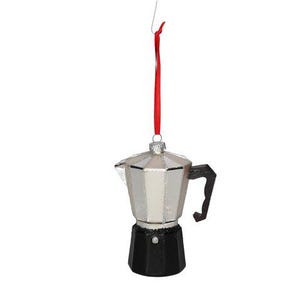 May include: A glass ornament shaped like a moka pot coffee maker. The upper section is silver with a metallic finish, while the base is black. A black handle is attached to the side, and a thin red ribbon is tied to the top for hanging purposes.