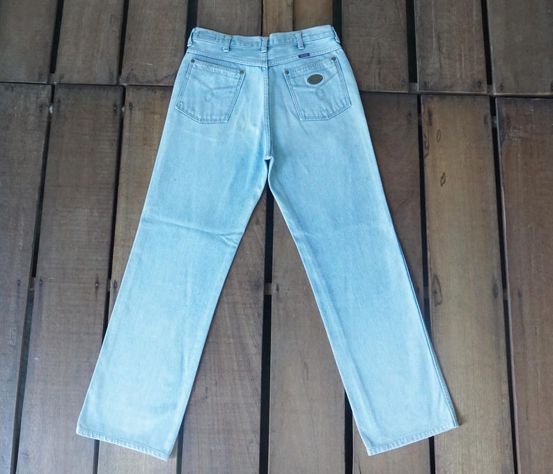 May include: Light blue denim jeans with a classic five-pocket design. The jeans have a straight leg cut and a faded wash. The back pockets feature a simple design, and there is a small patch on the back waistband.