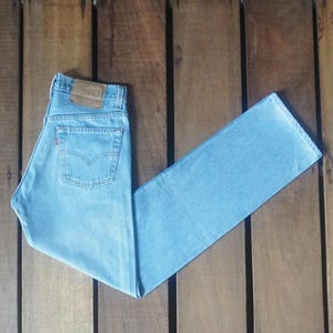 Puede incluir: Vaqueros de mezclilla azul claro con un parche de cuero marrón en la parte posterior de la cintura.