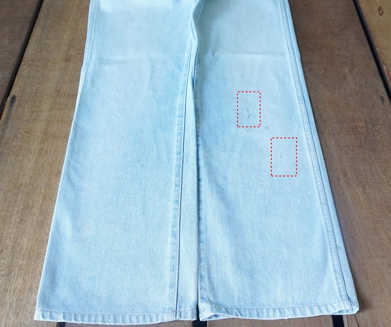 May include: Light blue denim pants with a wide leg design. The pants have a classic five-pocket style and a button and zipper closure. The denim has a faded wash and a slight distressed look.