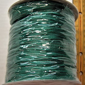 Può includere: Un rocchetto di cordoncino di cotone cerato verde scuro avvolto in plastica trasparente.