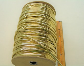 May include: A spool of gold metallic cord, approximately 7 inches long, with a ruler for scale.