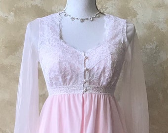 May include: A pink sheer nightgown with white lace trim and a button-up front. The gown has long sleeves and a fitted bodice. It is displayed on a white mannequin.