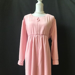 May include: A pink fleece robe with long sleeves and a zipper closure. The robe has a gathered waist and a simple design.