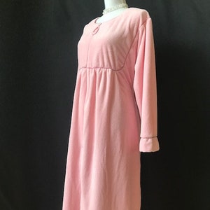 May include: A pink long-sleeved robe with a button closure and a gathered waist.