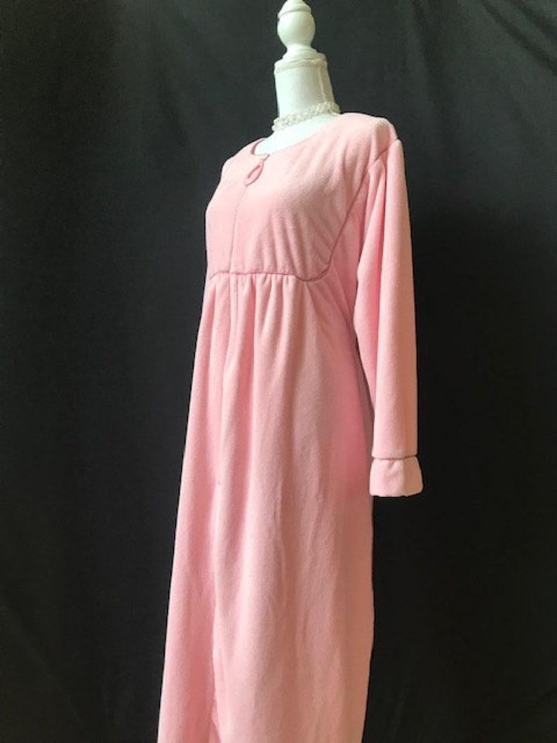 May include: A pink long-sleeved robe with a button closure and a gathered waist.