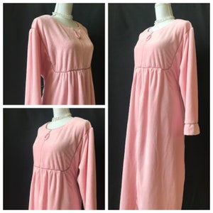 May include: A pink long-sleeved robe with a tie at the neck and a gathered waist.