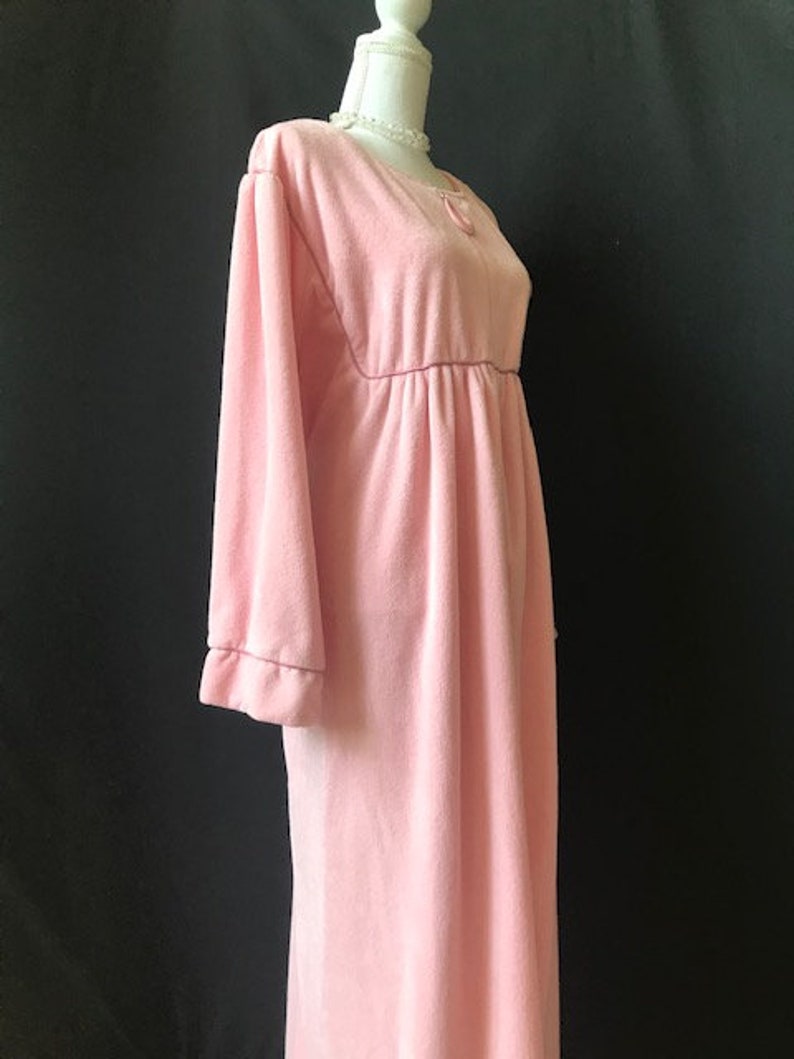 May include: A long, pink, velour robe with long sleeves and a gathered waist.