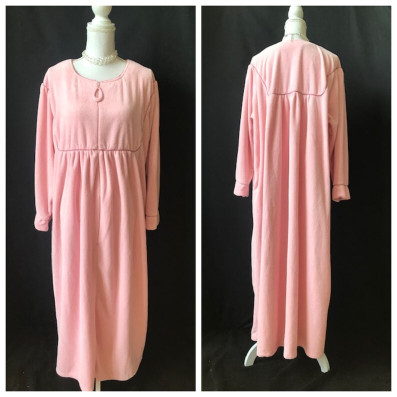 May include: A long pink robe with a zipper closure and long sleeves. The robe is made of a soft, plush fabric.