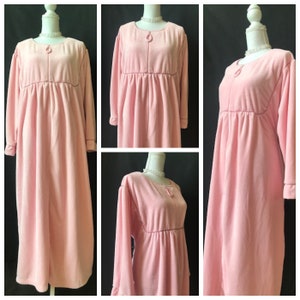 May include: A long, pink, fleece robe with a zipper closure and long sleeves. The robe has a gathered waist and a simple, elegant design.