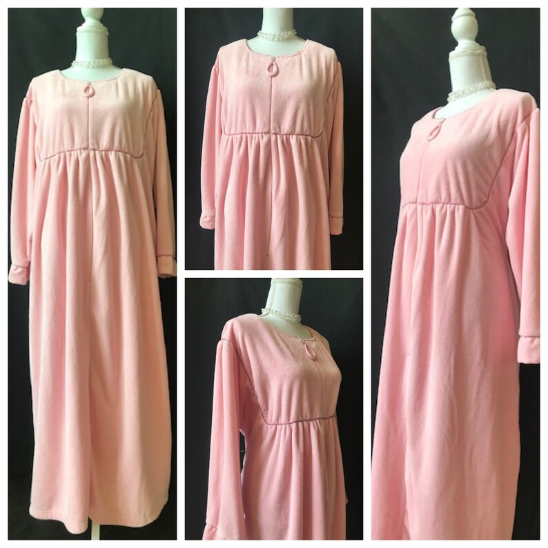 May include: A long, pink, fleece robe with a zipper closure and long sleeves. The robe has a gathered waist and a simple, elegant design.