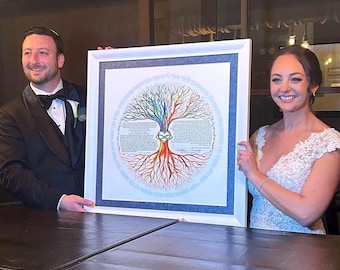 May include: A framed artwork featuring a colorful tree design with a heart-shaped knot in the center. The artwork is held by a couple, the man in a tuxedo and the woman in a white lace dress. The artwork has a white frame and a blue border.