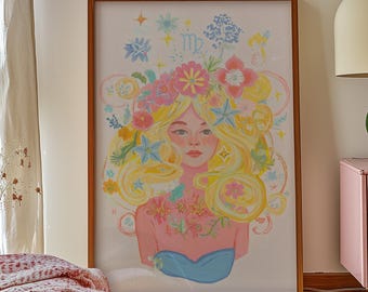 Op de afbeelding: Een ingelijst afdruk van een kleurrijke illustratie van een vrouw met een bloemenkrans en het astrologische symbool voor Maagd. De achtergrond is wit met een paar sterren.