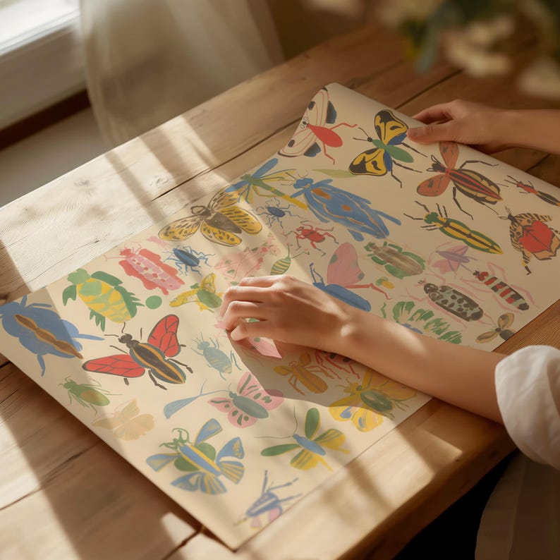 May include: A vintage-style wrapping paper featuring a colorful pattern of butterflies, beetles, and other insects. The paper is folded in half and a hand is reaching out to touch it.