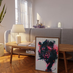 May include: A framed abstract painting of a lion with pink, black, and white paint. The painting is hanging on a wall in a living room with a wooden coffee table and a gray sofa.